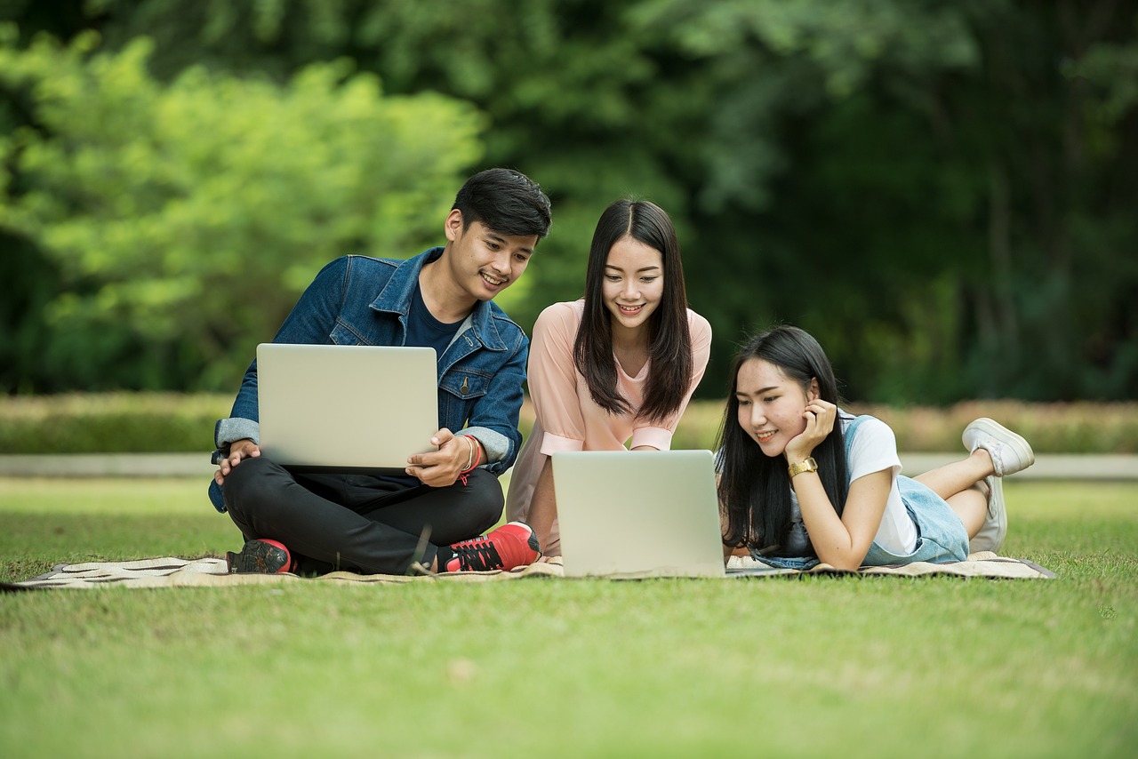 芝生の上でpcを見てる男女